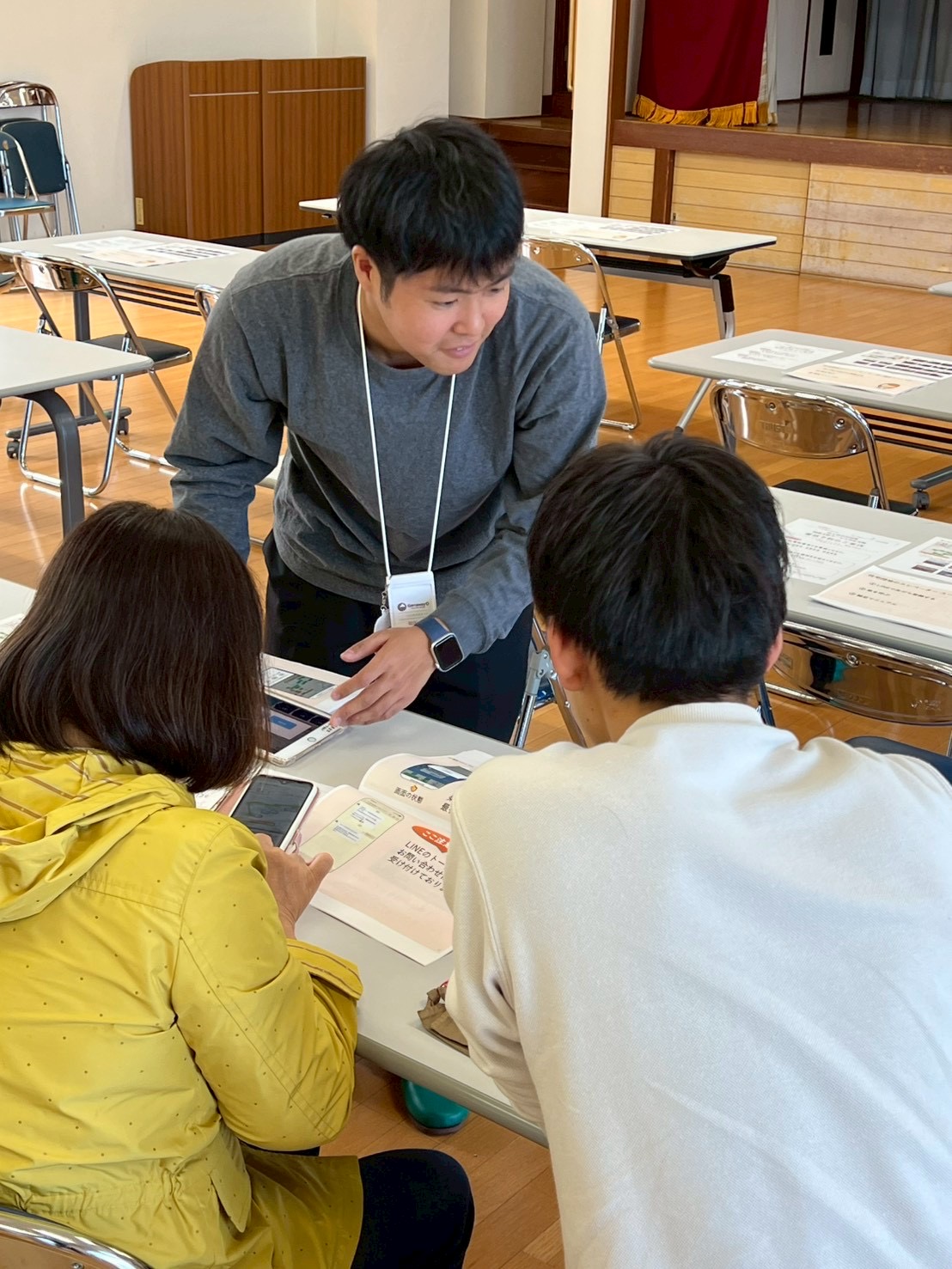 住民説明会で、スタッフがタブレットと紙の資料を使って参加者に説明している